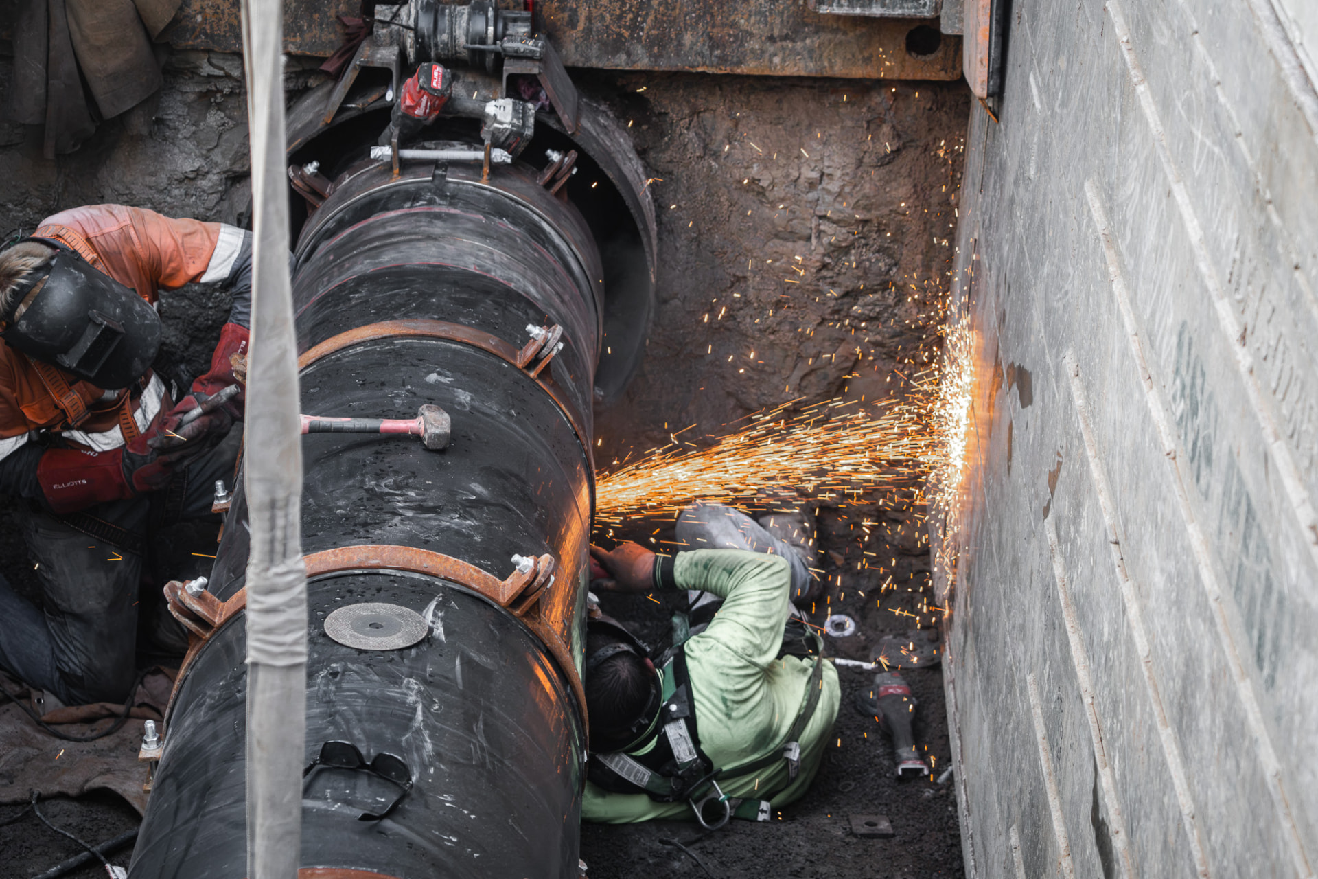 Workers grinding a large pipeline in a trench